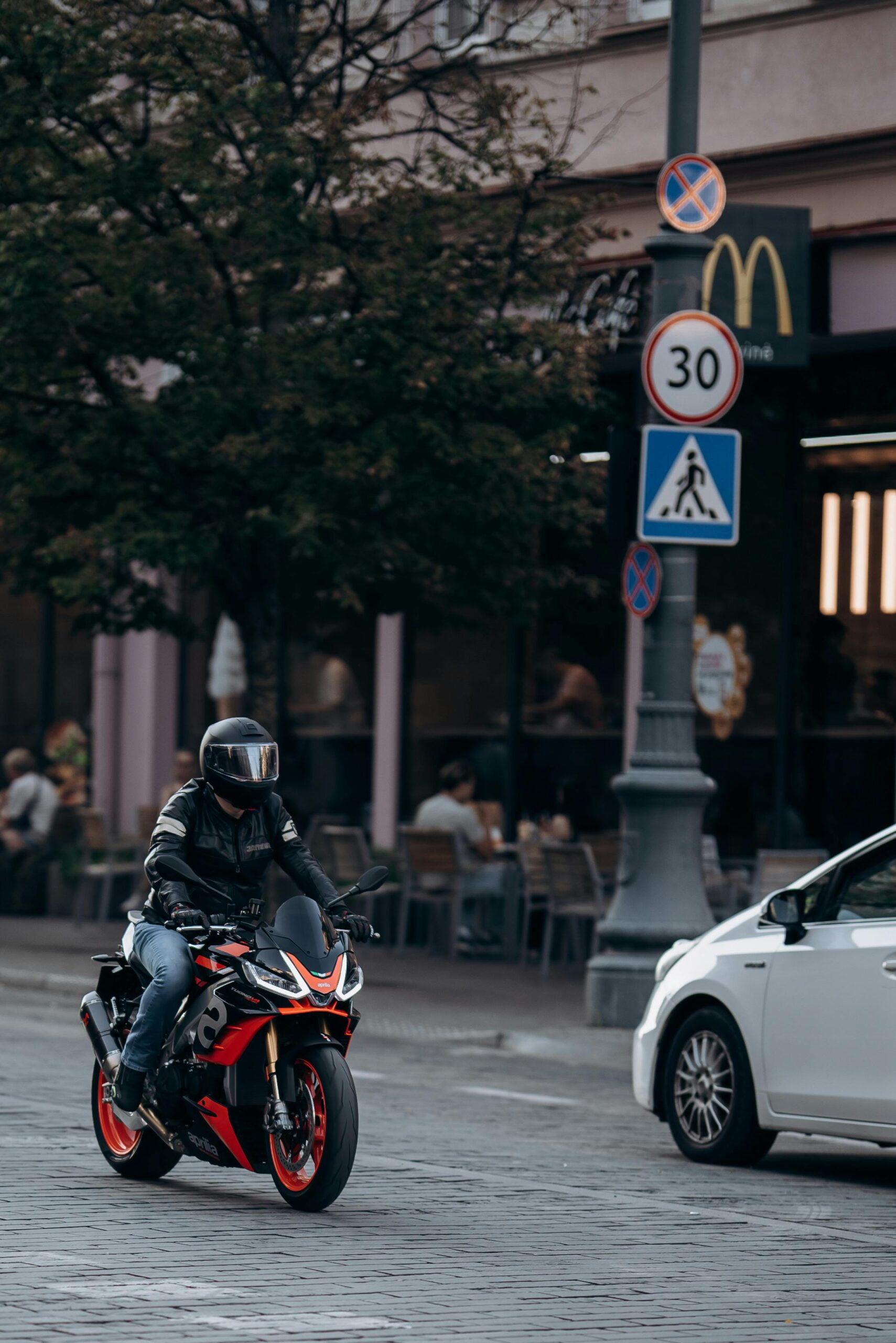 Motorcyclist riding through city street with traffic signs and buildings.